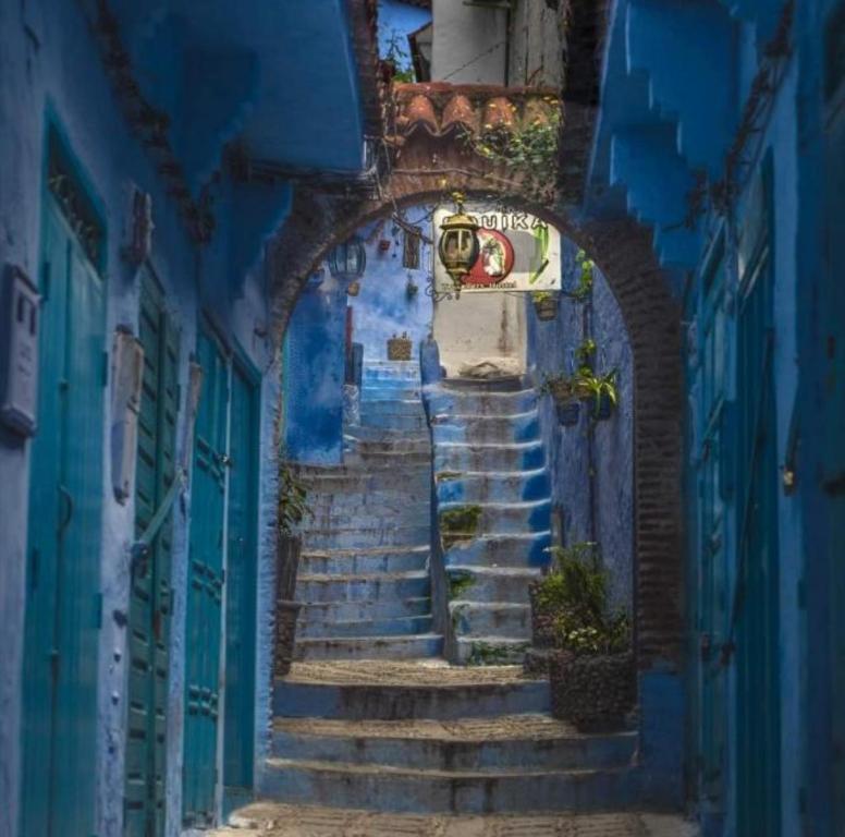 an alley with stairs in a blue building at Hotel Souika in Chefchaouene