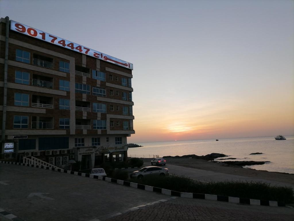 a hotel on the beach with the sunset in the background at Amwaj hotel Salalah Mirbat in Salalah