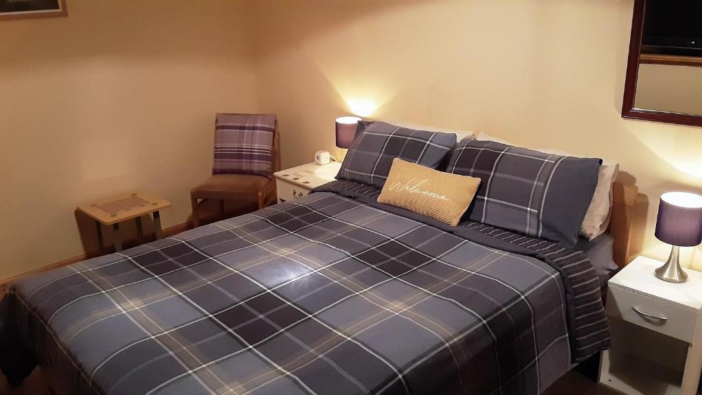 a bedroom with a blue bed and a chair at Hamnavoe John o Groats Hostel in John O Groats