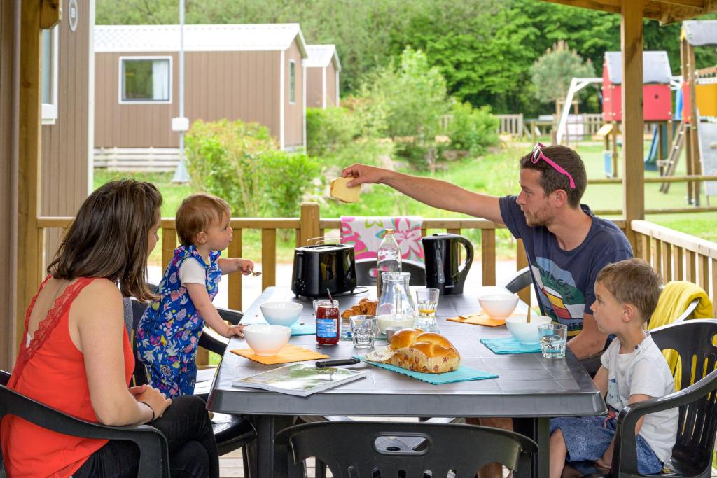 a group of people sitting around a table with food at Camping Capfun La Bretèche in Les Épesses