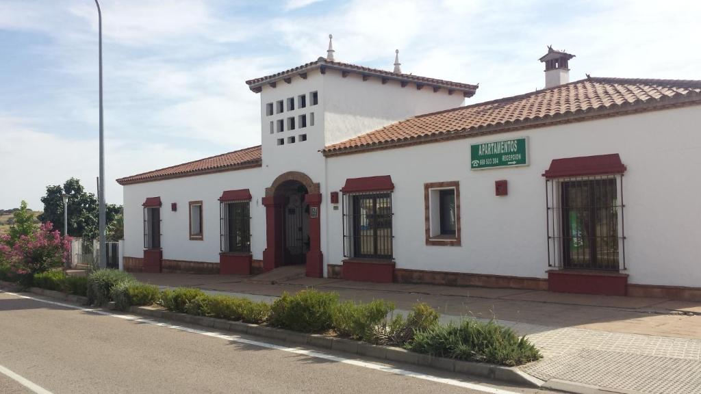 un edificio blanco con una torre de reloj en una calle en Apartamentos Turísticos - Hostal Los Alisos en Aliseda