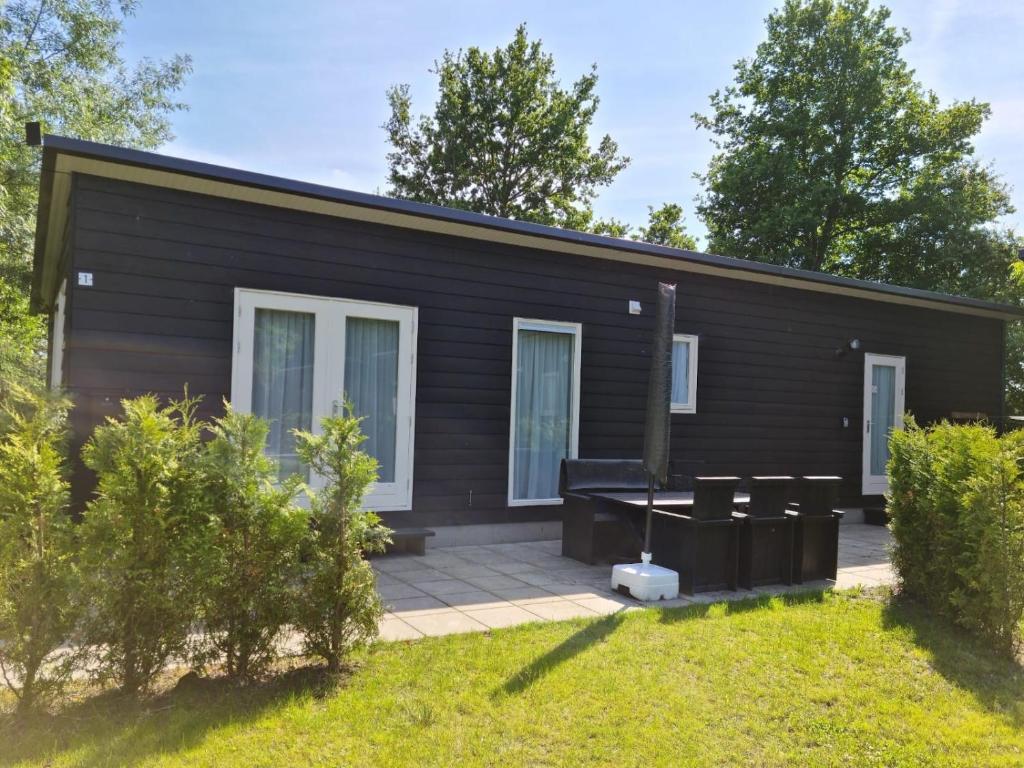a small black house with a patio at de4SeiZoentjes in Schoonebeek