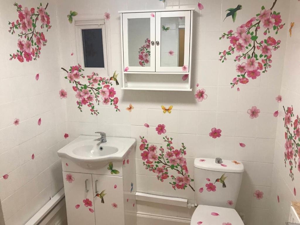 Baño con flores rosas en la pared en Bob's House quiet retreat in 3 bed house with gym en Loughborough