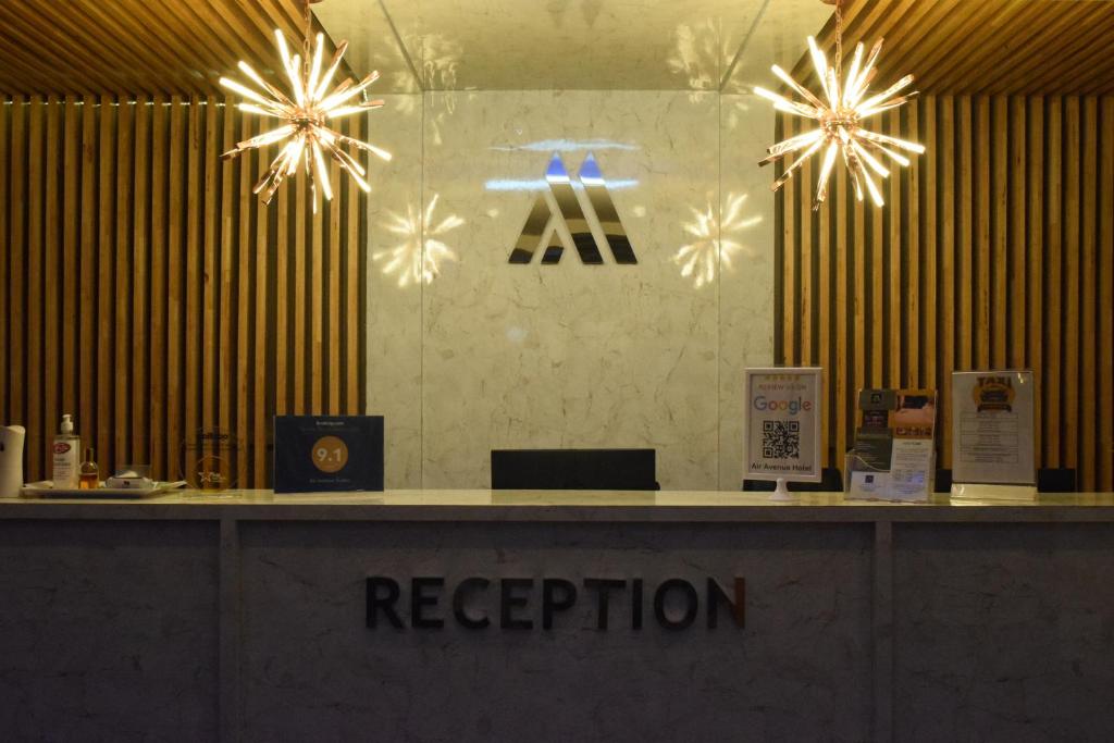 a reception desk with aaa sign on a wall at Air Avenue Hotel - Airport in Devanhalli