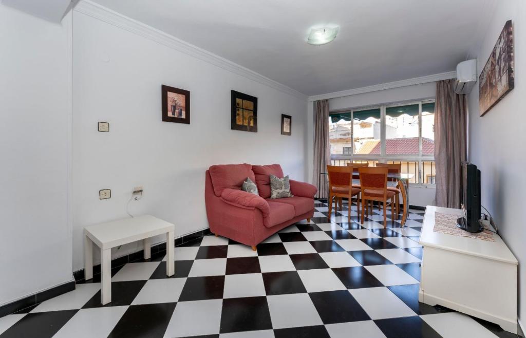 sala de estar con silla roja y suelo a cuadros en Malaga downtown and beach apartment, en Málaga