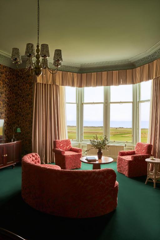 a living room with red chairs and a table and windows at Marine North Berwick in North Berwick