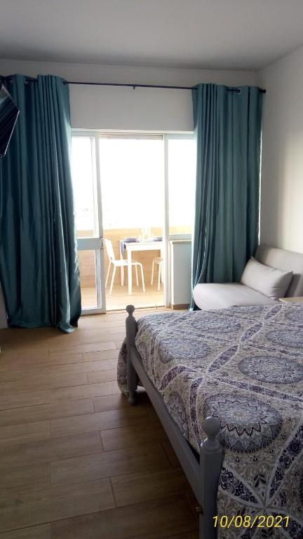 a bedroom with a bed with green curtains and a balcony at Sol e Praia Alvor 2 in Alvor