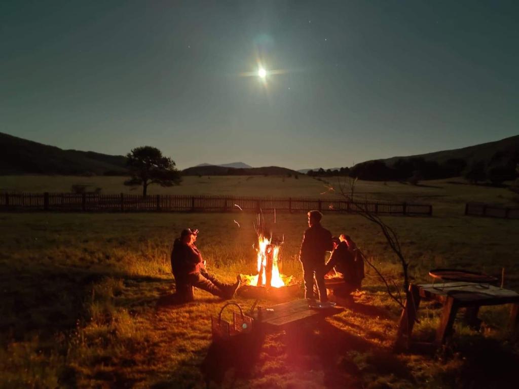a group of people sitting around a fire in a field at Ličke radosti in Lapac Gornji