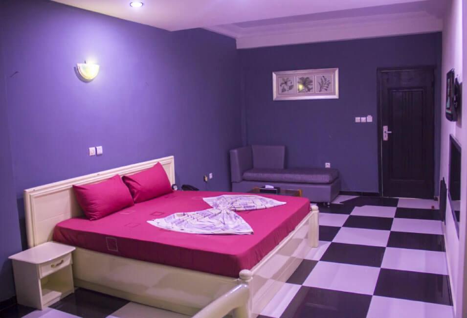 um quarto roxo com uma cama e um piso xadrez em Mosaly Hotel PK10 em Porto Novo