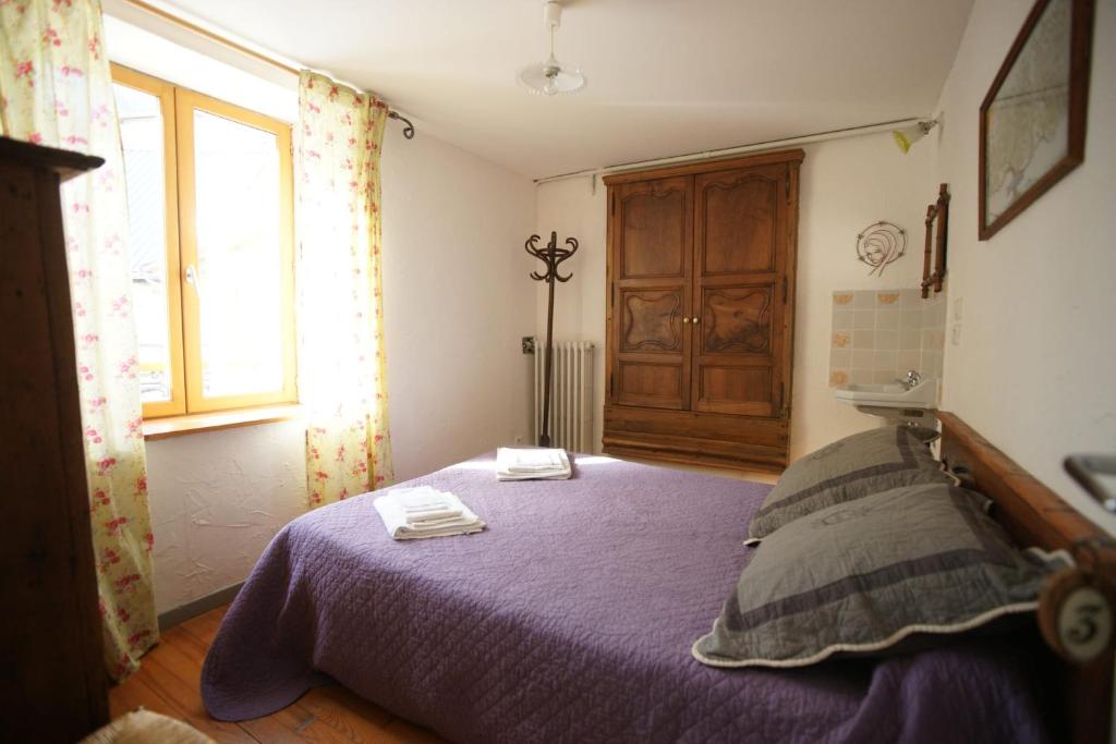 Un dormitorio con una cama con sábanas moradas y una ventana en Room for two in a house of the XVII century - N3 Chez Jean Pierre, en Villar-dʼArène