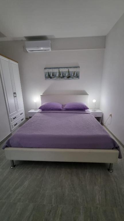 1 dormitorio con 1 cama grande con almohadas moradas en Room Airport Split en Kaštela