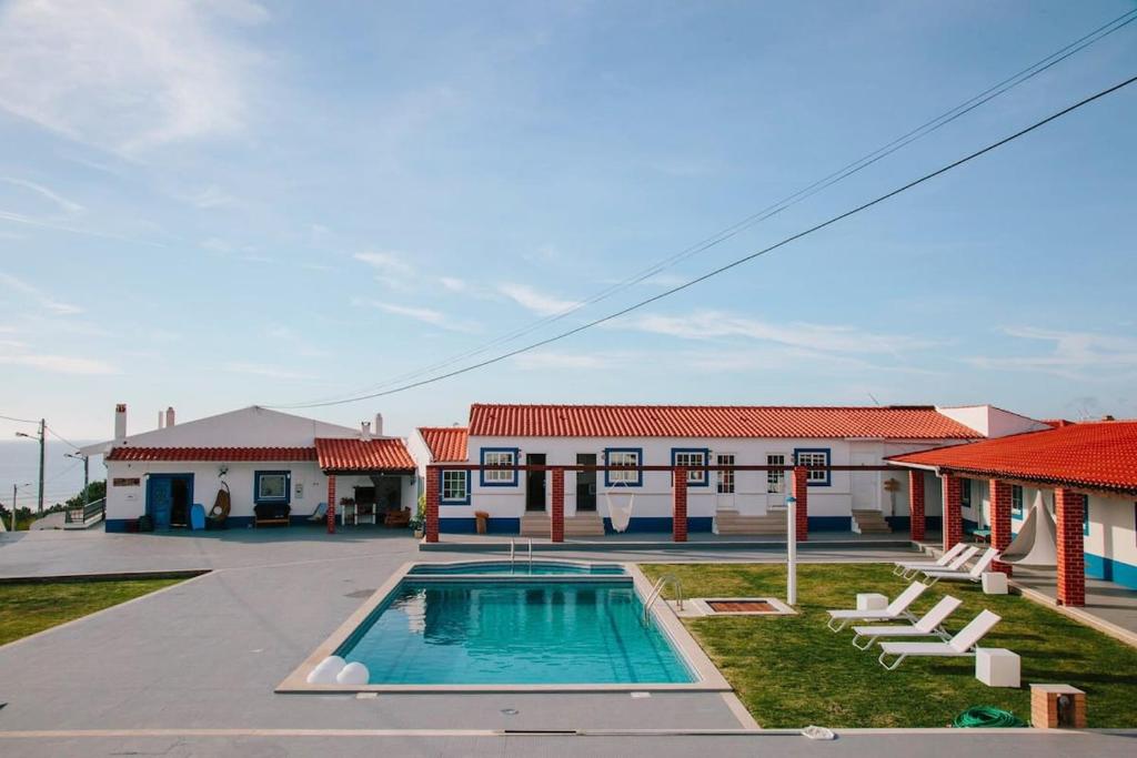 a house with a swimming pool in front of a building at Zulla House in Nazaré