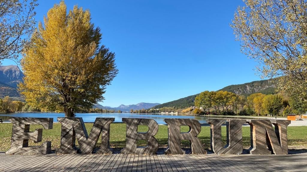 a sign in front of a lake with mountains in the background at Embrun - Appartement 4&#47;6 personnes avec extérieurs in Embrun