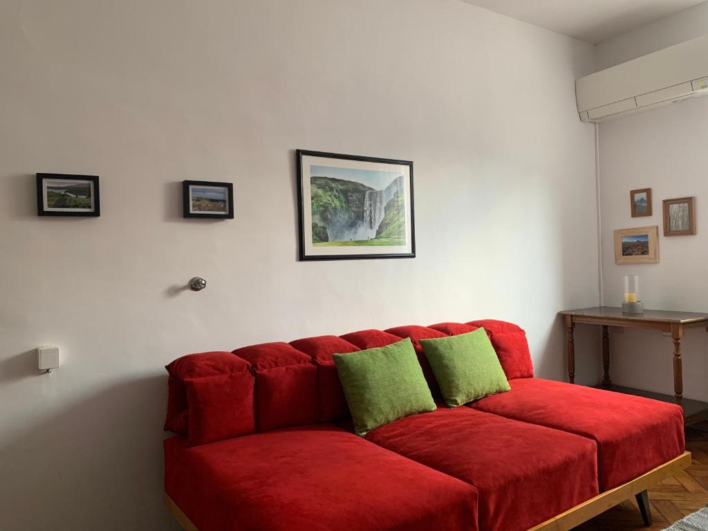 New episode - apartment with private parking في ليوبليانا: أريكة حمراء مع وسادتين خضراء في غرفة المعيشة