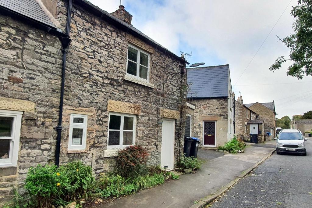 uma casa de pedra com um carro estacionado em frente em Hope Cottage, Great Longstone em Great Longstone