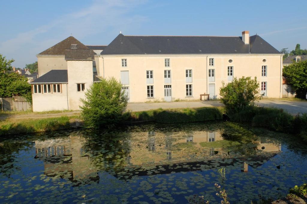 un grand bâtiment blanc avec une réflexion dans un corps d'eau dans l'établissement Gîte des Grands Moulins de Baugé, à Baugé