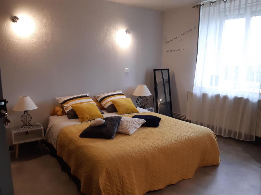 1 dormitorio con 1 cama grande con mantas y almohadas amarillas en ferme des champs en Vrécourt