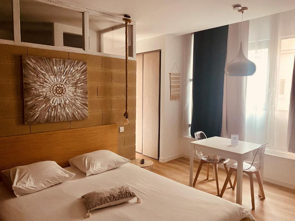 1 dormitorio con cama, mesa y mesa en Suite 24 Appart'hôtel-3 étoiles, en Le Creusot