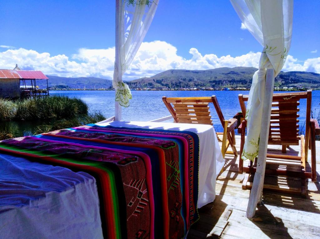 a table and chairs on a deck with a view of the water at Titicaca wasy lodge in Puno