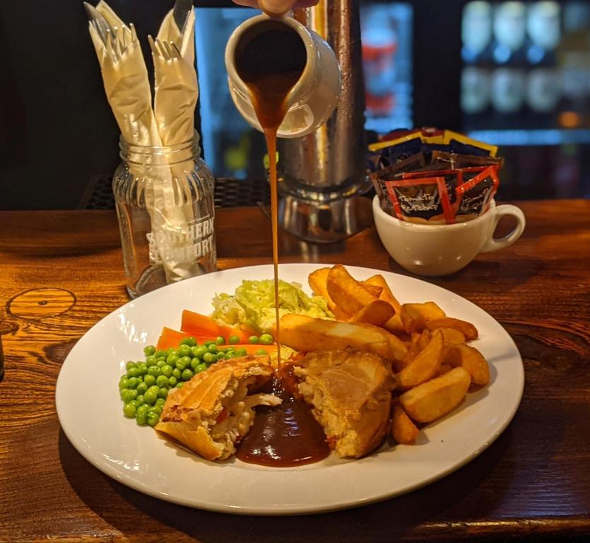 a plate of food with a sandwich and potatoes and peas at Linden Tree in Gloucester