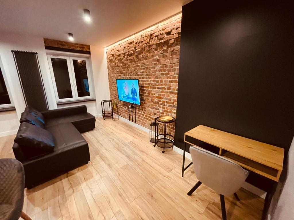 een woonkamer met een bank en een bakstenen muur bij Apartamenty KTW Park Śląski in Katowice