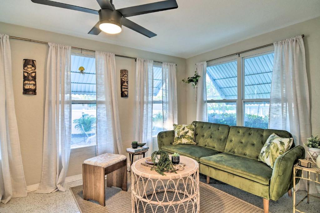 a living room with a green couch and windows at Lush Seminole Surf Inn with Backyard Fire Pit! in Seminole