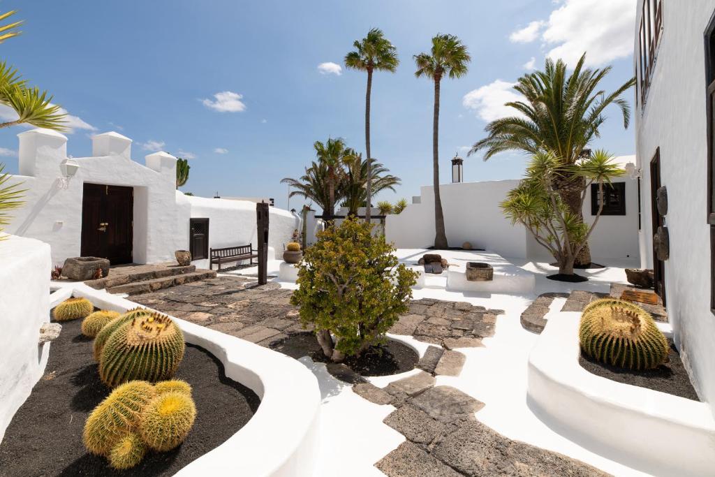 a garden with cacti and palm trees and a building at Las Pérgolas Villa Rural in Tías