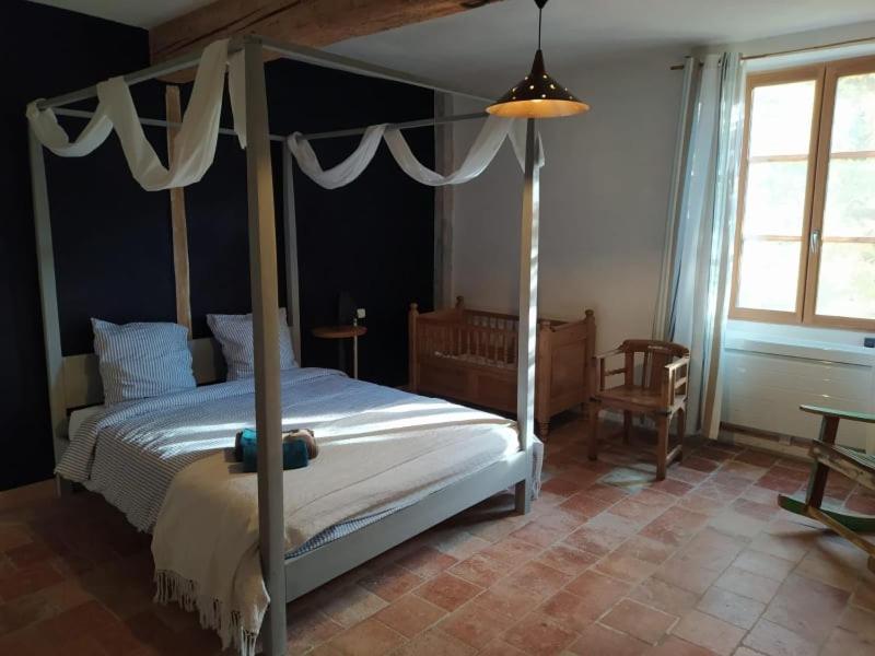 a bedroom with a canopy bed and a table at Les Amis de Gaure in Rouffiac-dʼAude