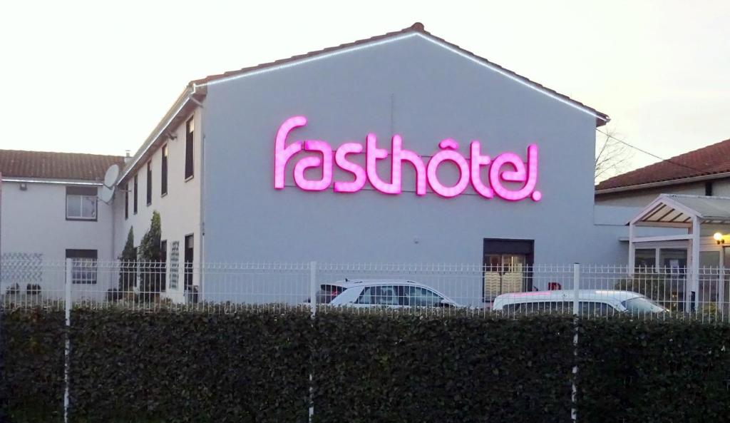 een wit gebouw met een neonbord erop bij Fasthotel Tarbes Séméac - Un hôtel FH Confort in Séméac