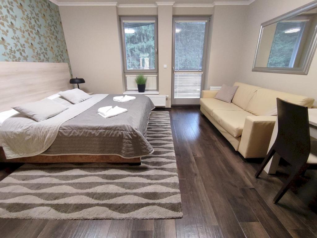 ein Schlafzimmer mit einem Bett und einem Sofa in der Unterkunft Útulné studio s balkónem in Harrachov
