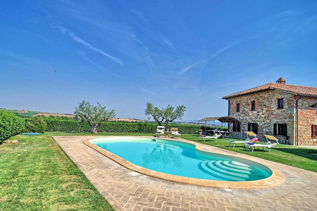 una piscina frente a una casa de piedra en Cottage Casaglia en Paciano