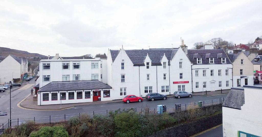 un grupo de edificios blancos con coches estacionados en un estacionamiento en The Royal Hotel, en Portree