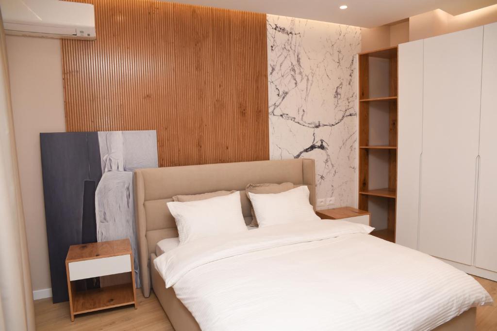 J&D Rooms Korce في كورتشي: غرفة نوم بسرير كبير مع شراشف بيضاء
