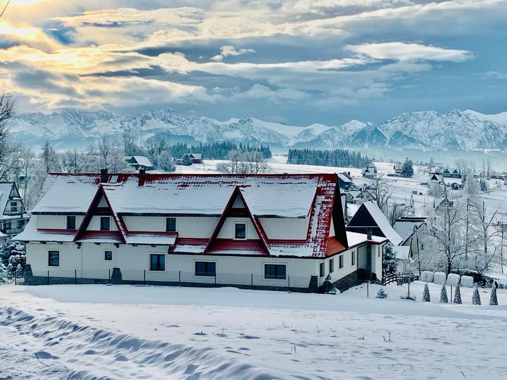 ein weißes Haus mit rotem Dach im Schnee in der Unterkunft Ośrodek Wypoczynkowy u Bartka in Czerwienne