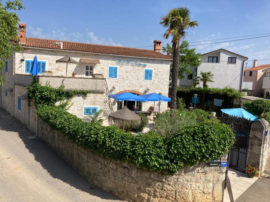 una pared de piedra con sombrillas azules y un edificio en B&B Nostromo en Funtana