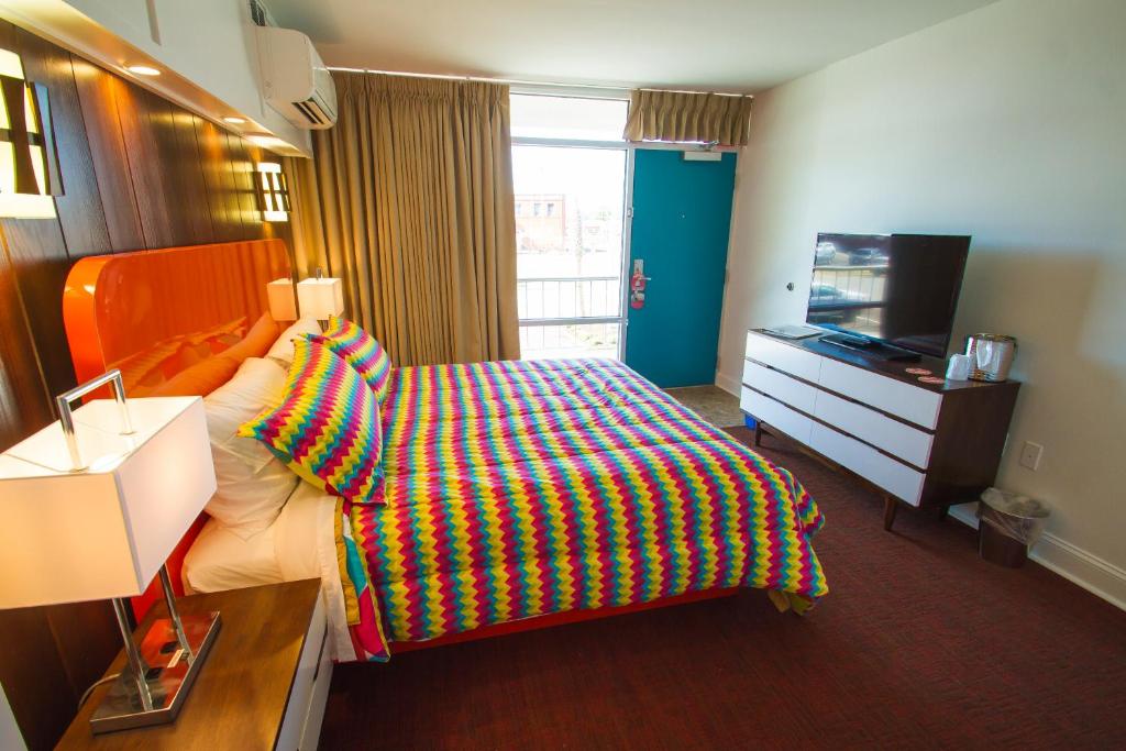 a bedroom with a bed with a colorful blanket on it at Mother Earth Motor Lodge in Kinston