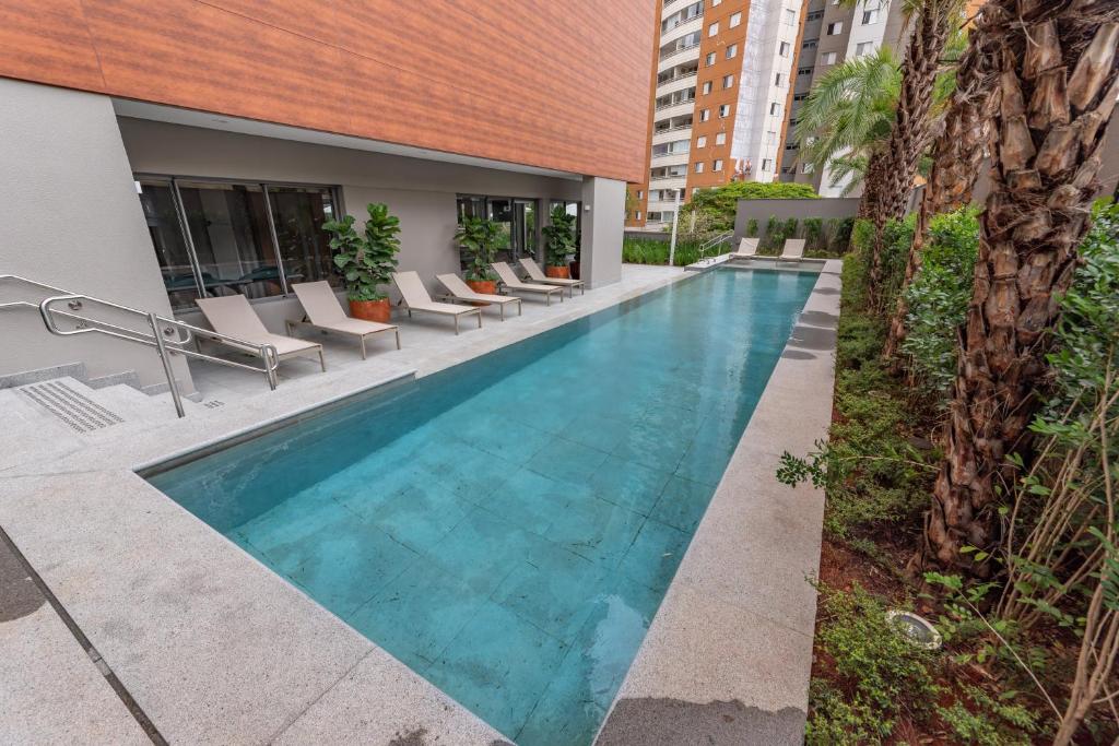 a swimming pool with lounge chairs next to a building at Charlie Vitrali Moema in São Paulo