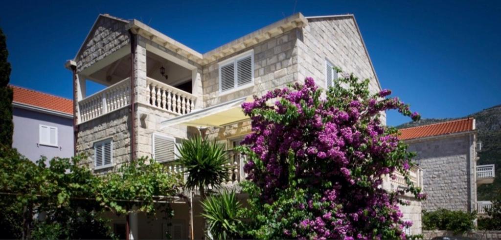 una grande casa con fiori viola di fronte di Relax Comfy Cozy Apartment a Cavtat