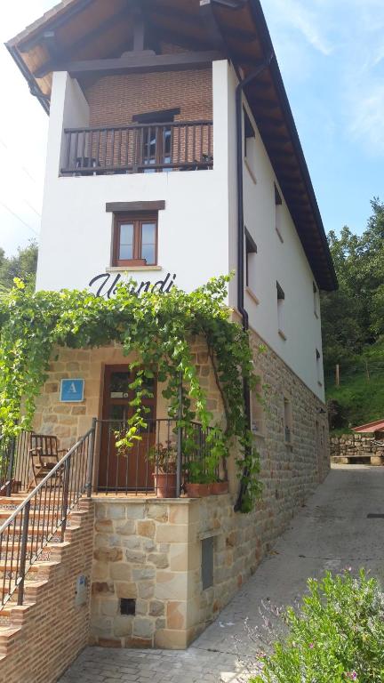 a building with a balcony and stairs in front of it at Albergue Usandi Auto Check-in in Ziortza-Bolibar