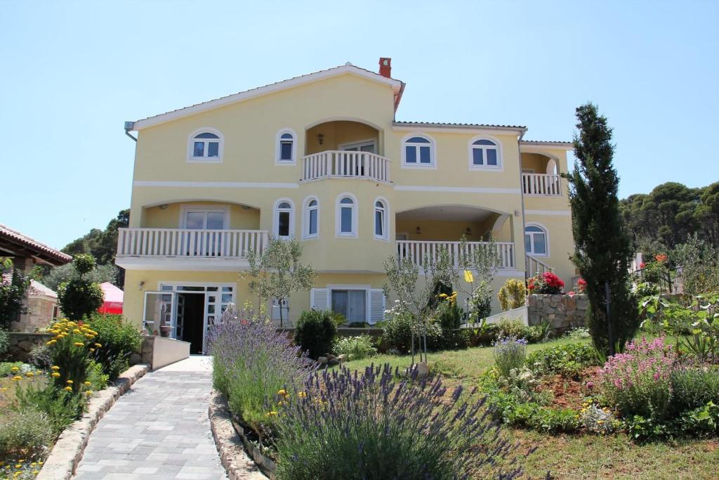 une grande maison avec un jardin en face de celle-ci dans l'établissement Apartments Villa Lora, à Kraj