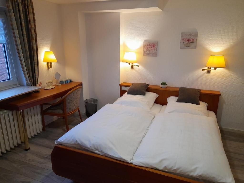 2 Betten in einem Zimmer mit einem Schreibtisch und 2 Lampen in der Unterkunft Hotel Zurmühlen in Sendenhorst