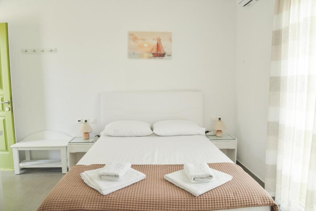 a white bedroom with a bed with towels on it at Zeras Apartments in Adamantas