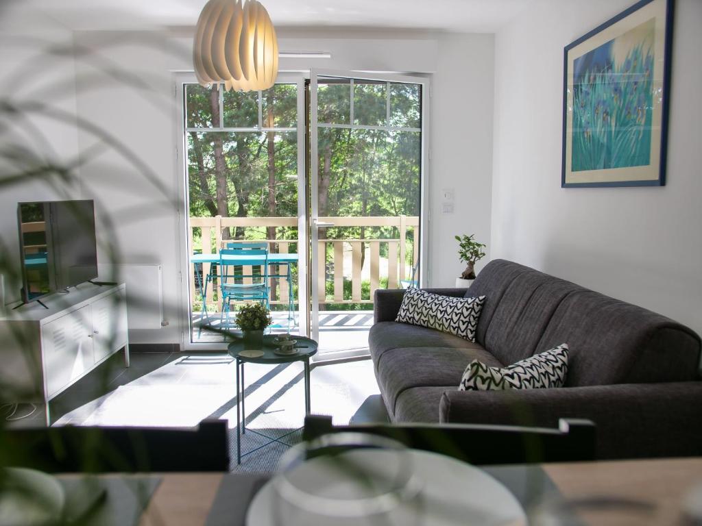 a living room with a couch and a large window at Apt. neuf à 50m du port - Parking privé, ascenseur in Saint-Valery-sur-Somme