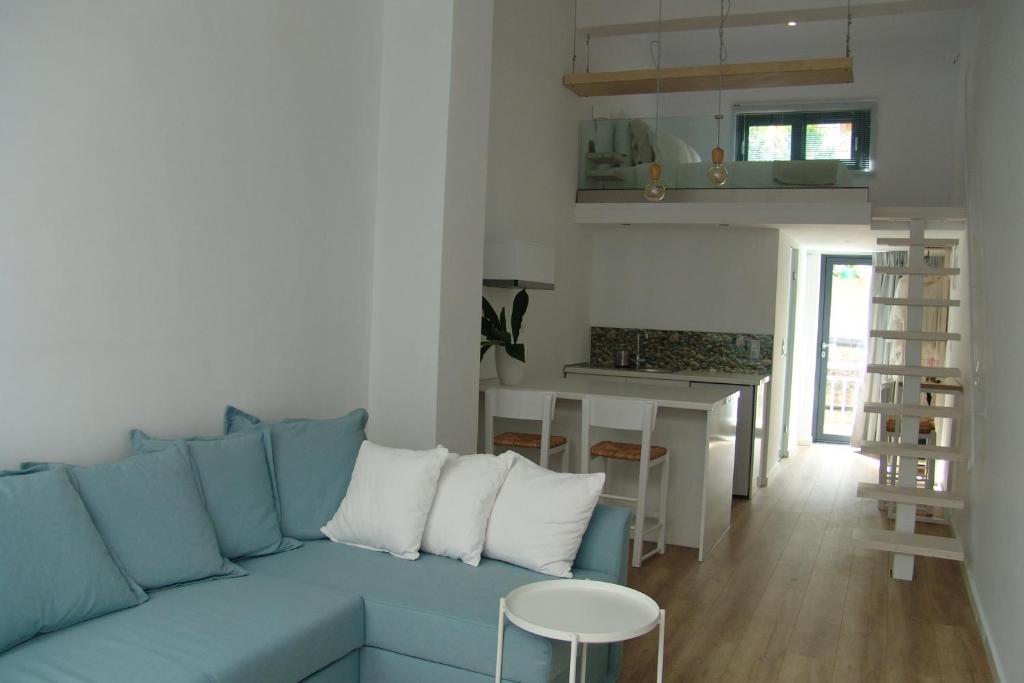 a living room with a blue couch and a kitchen at Sixteen All Seasons House in Chania