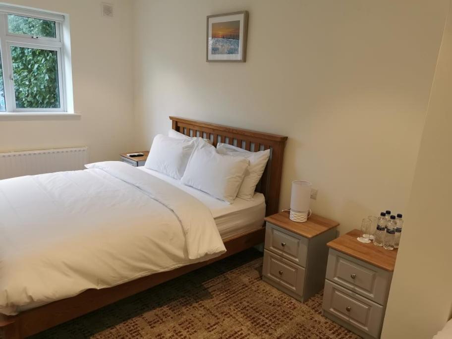 a bedroom with a bed with white sheets and two night stands at Coliemore Acommodation Dalkey in Dalkey