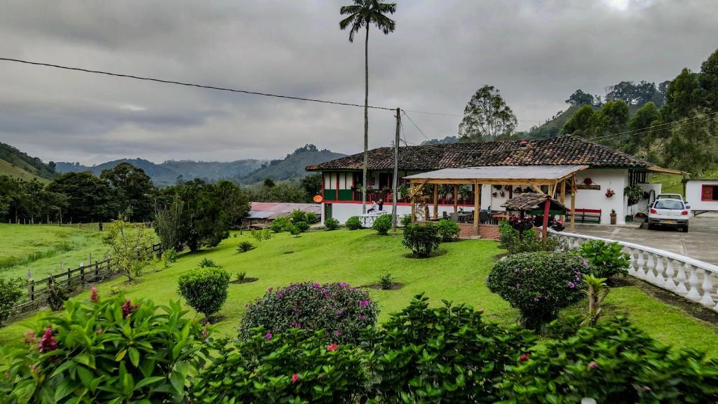 a house with a green lawn in front of a building at Finca La Playa Ecohotel - Experiencia Campestre - in Salento