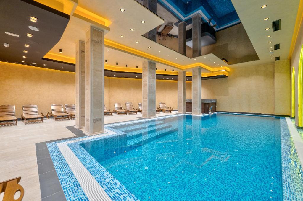 a large swimming pool in a building with chairs at Sunset Lux S3 Wellness & Spa Zlatibor in Zlatibor