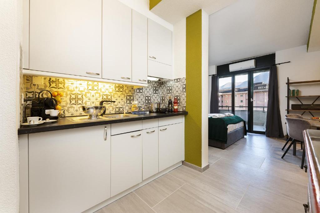 una cucina con mobili bianchi e un soggiorno di Monolocale con terrazzo vista lago Via Cassarinetta 7 by LR a Lugano