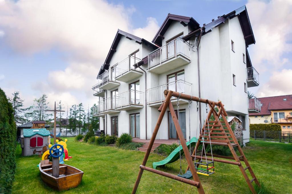 uma casa com um parque infantil em frente em Pokoje VIERA em Karwia