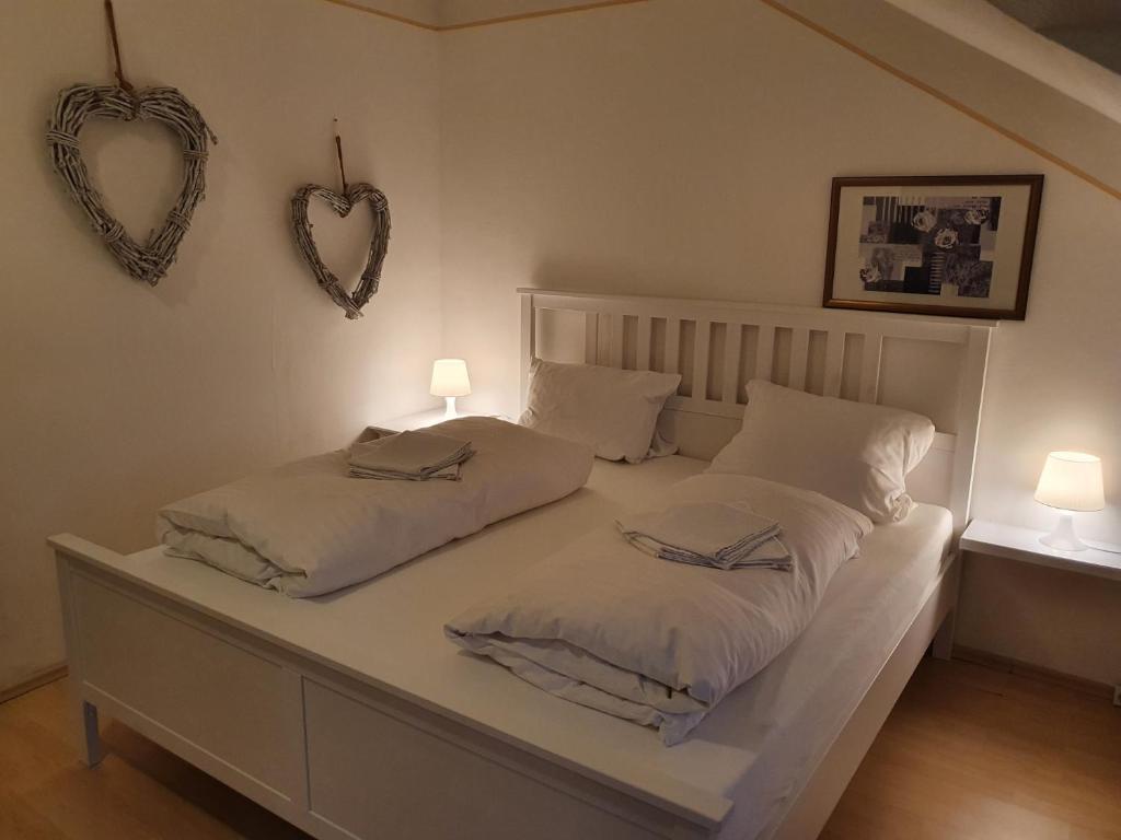 een wit bed met twee kussens en twee harten aan de muur bij CityPark Aparthotel in Keulen